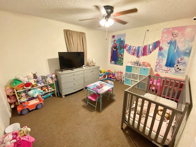 bedroom with a crib, ceiling fan, carpet, and a textured ceiling