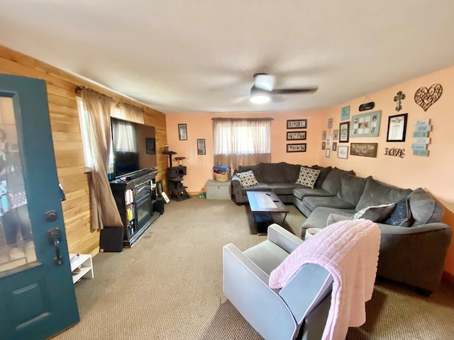 carpeted living room with wooden walls and ceiling fan