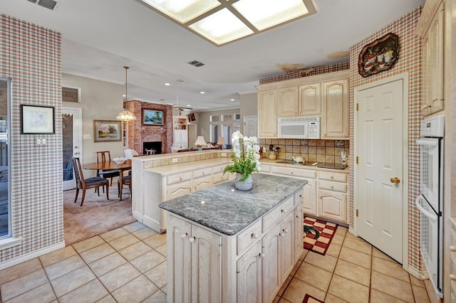 kitchen featuring hanging light fixtures, light tile patterned floors, kitchen peninsula, a kitchen island, and white appliances