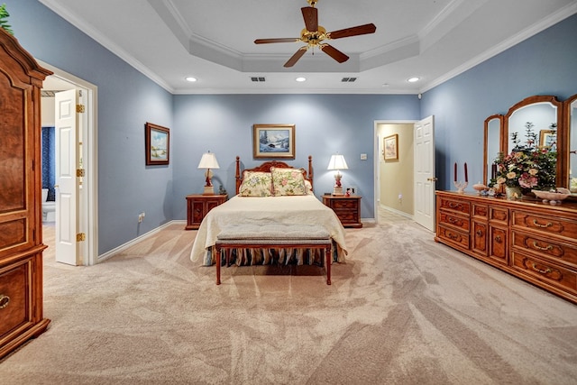 carpeted bedroom featuring crown molding, ensuite bath, ceiling fan, and a tray ceiling