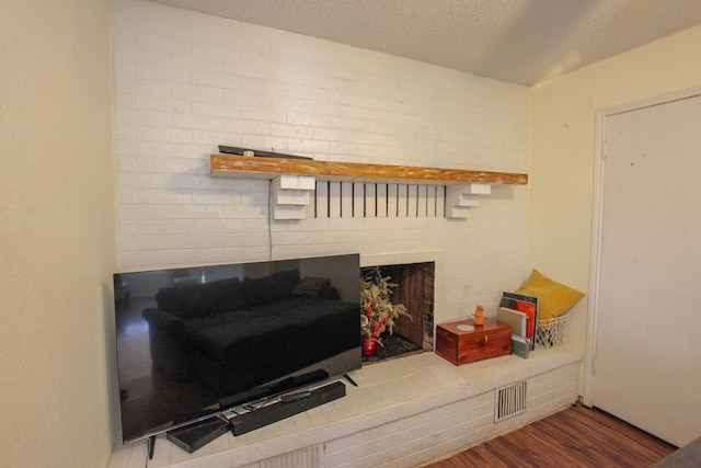 living room featuring wood-type flooring, a textured ceiling, and a fireplace