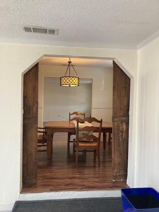 dining room featuring a textured ceiling, hardwood / wood-style floors, and crown molding