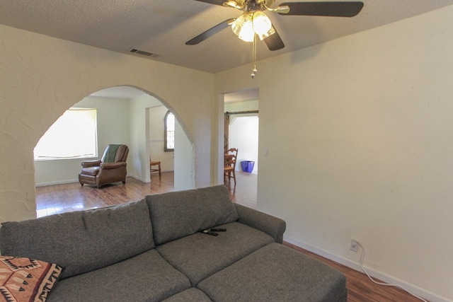 living room featuring hardwood / wood-style floors, a textured ceiling, and ceiling fan