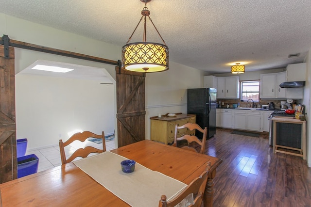 dining space featuring a textured ceiling, a barn door, and hardwood / wood-style flooring