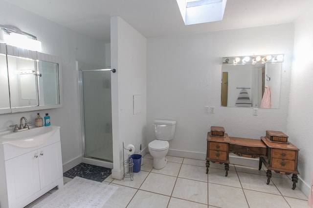 bathroom featuring tile patterned flooring, toilet, a skylight, vanity, and a shower with door