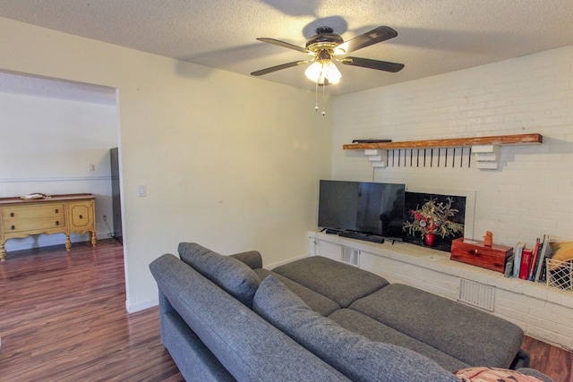 living room with a textured ceiling, dark wood-type flooring, brick wall, and ceiling fan