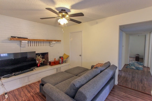 living room featuring dark wood-type flooring, a textured ceiling, and ceiling fan