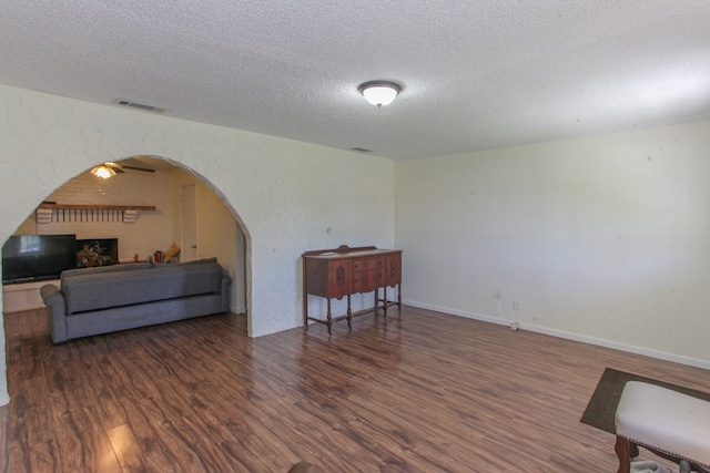 interior space featuring a textured ceiling, ceiling fan, and dark wood-type flooring