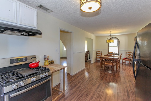 kitchen with black refrigerator, gas stove, pendant lighting, dark hardwood / wood-style floors, and white cabinets