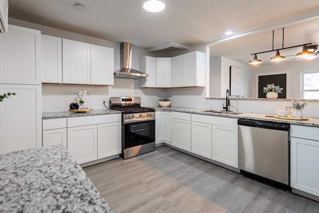 4604 Versailles Dr, Midland, TX 79703 - kitchen featuring appliances with stainless steel finishes, wall chimney range hood, light wood-style flooring, white cabinets, and recessed lighting