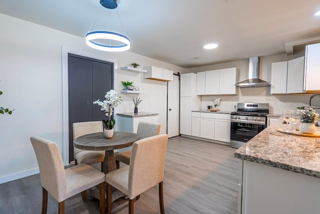 4604 Versailles Dr, Midland, TX 79703 - kitchen with stainless steel range with gas cooktop, wall chimney range hood, light stone countertops, white cabinets, and recessed lighting