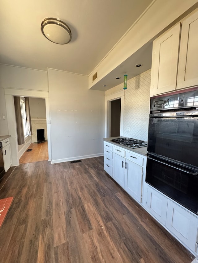 1912 29th St, Snyder, TX 79549 - kitchen featuring dark wood-type flooring, white cabinetry, double oven, and stainless steel gas cooktop