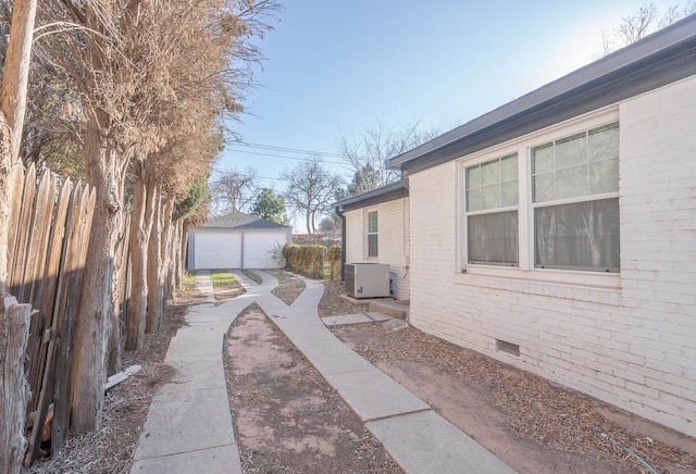 view of yard featuring an outbuilding, central AC unit, a detached garage, and fence