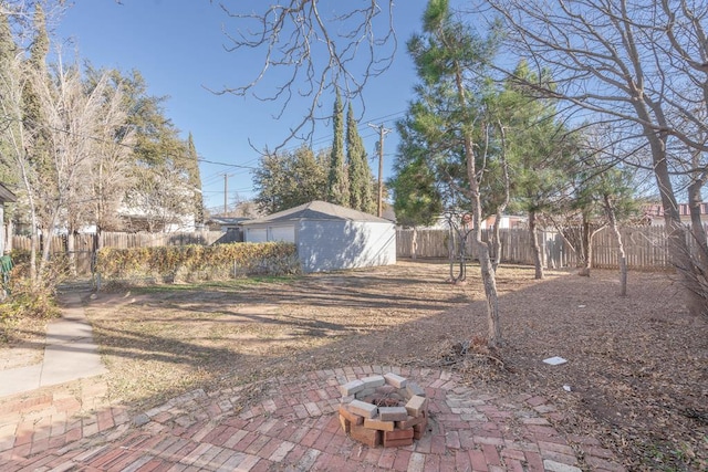 view of yard featuring a fire pit, a patio area, an outdoor structure, and a fenced backyard