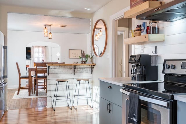 kitchen featuring under cabinet range hood, electric range, light countertops, light wood-type flooring, and gray cabinets