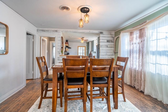 dining space with ornamental molding, visible vents, baseboards, and wood finished floors