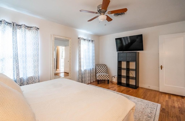 bedroom featuring baseboards, wood finished floors, visible vents, and a ceiling fan