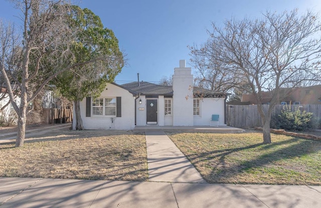 view of front of house featuring a chimney, fence, and a front yard