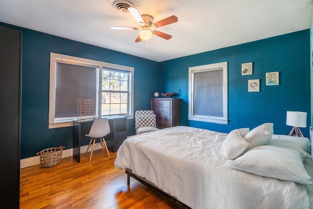 bedroom with visible vents, baseboards, ceiling fan, and wood finished floors