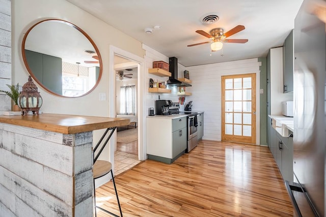 kitchen with visible vents, appliances with stainless steel finishes, light wood-type flooring, wall chimney range hood, and open shelves