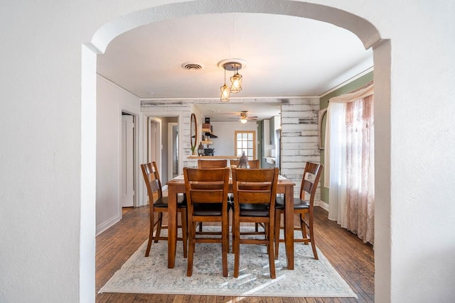 dining area featuring arched walkways, wood finished floors, visible vents, and baseboards