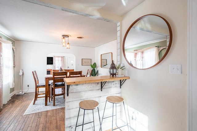 dining room with arched walkways, visible vents, plenty of natural light, and wood finished floors