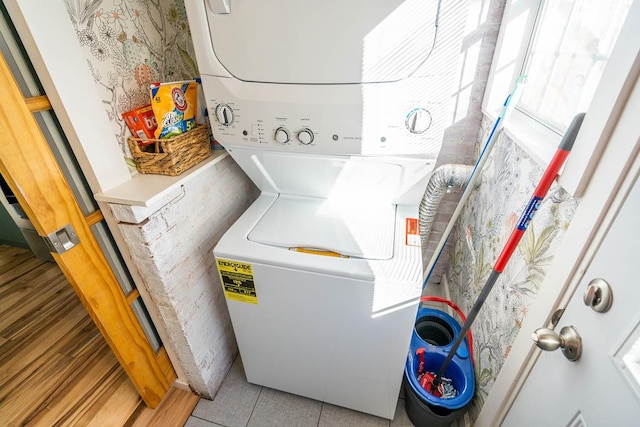 laundry area featuring laundry area, stacked washing maching and dryer, and wood finished floors