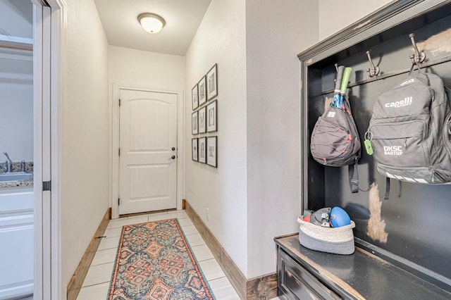 doorway to outside featuring light tile patterned floors, baseboards, and a sink