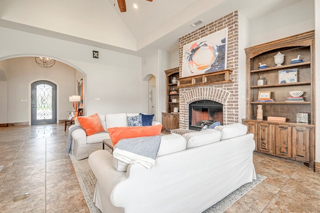 living area featuring arched walkways, high vaulted ceiling, a ceiling fan, a brick fireplace, and built in features