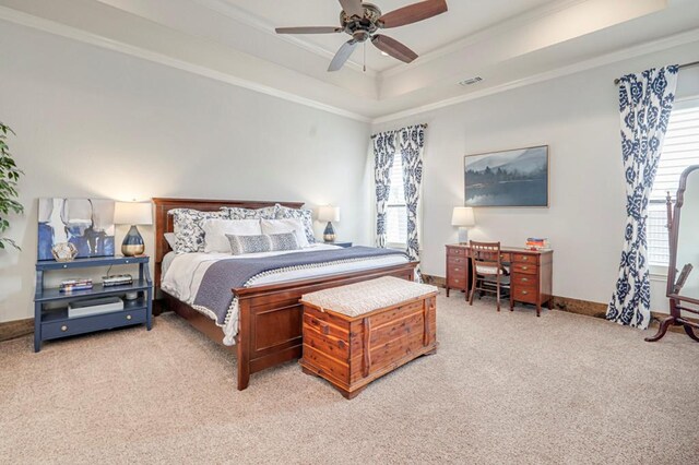 bedroom featuring multiple windows, light colored carpet, crown molding, a tray ceiling, and baseboards