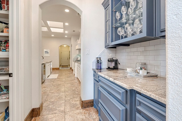 kitchen with blue cabinets, arched walkways, tasteful backsplash, recessed lighting, and baseboards