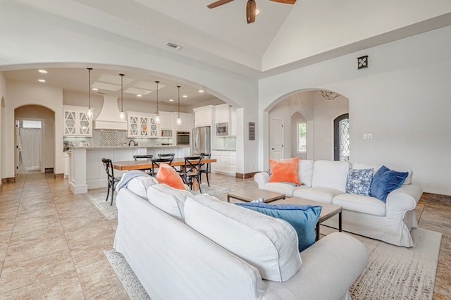 living room featuring a ceiling fan, high vaulted ceiling, arched walkways, and recessed lighting