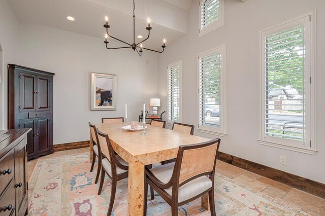 dining area with baseboards, a chandelier, stone tile floors, a towering ceiling, and recessed lighting