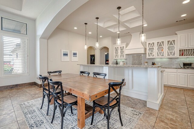 dining space featuring arched walkways, recessed lighting, coffered ceiling, bar with sink, and light tile patterned flooring
