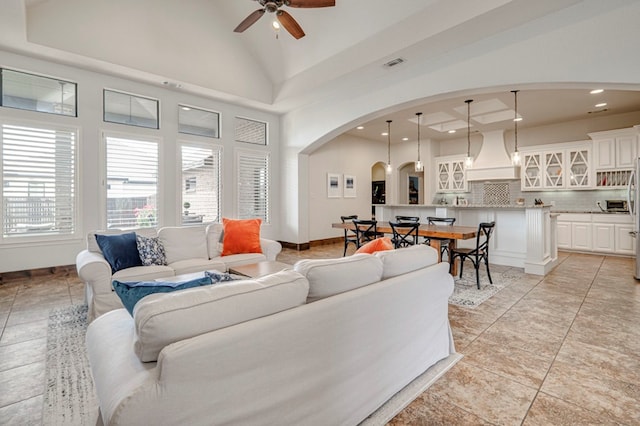 living area with arched walkways, a ceiling fan, recessed lighting, vaulted ceiling, and baseboards