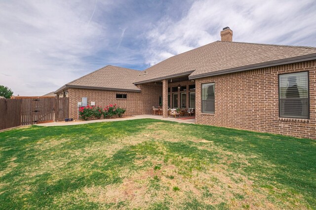 rear view of house featuring brick siding, roof with shingles, a chimney, a patio, and a gate