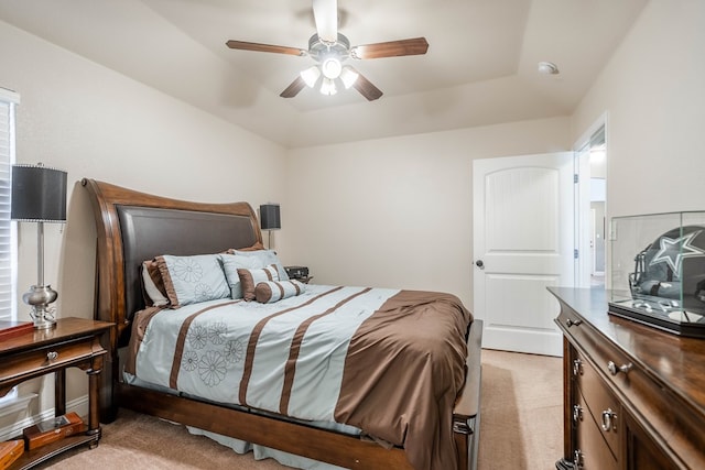 bedroom with ceiling fan, light carpet, and a tray ceiling