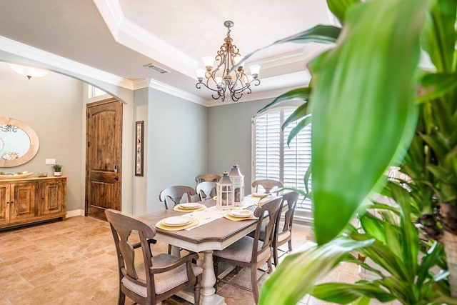 dining room with an inviting chandelier, a raised ceiling, stone finish flooring, crown molding, and visible vents