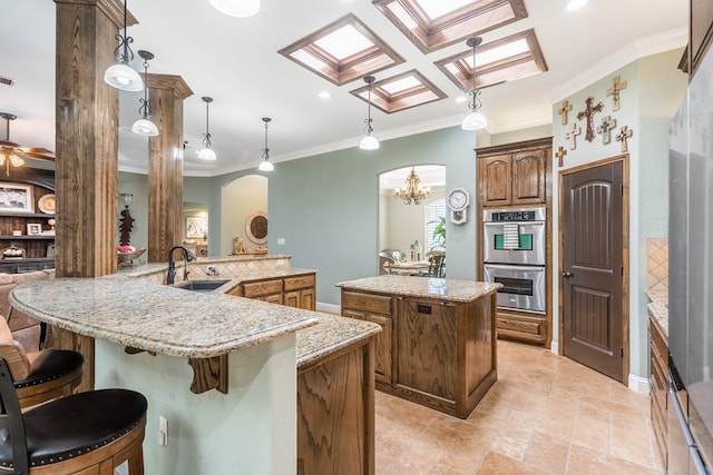 kitchen featuring a sink, a spacious island, ornamental molding, double oven, and arched walkways