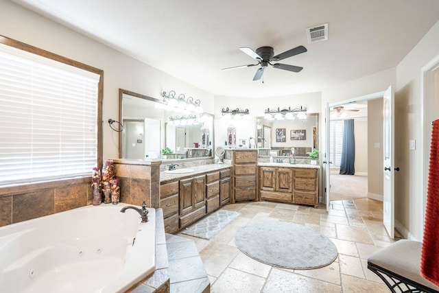 full bathroom featuring vanity, stone tile flooring, ceiling fan, visible vents, and a jetted tub