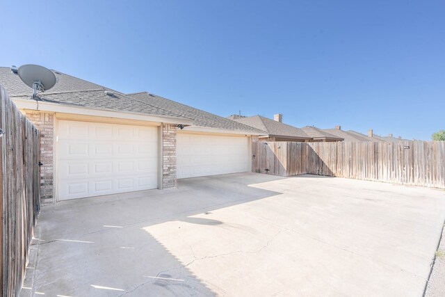 garage with fence and concrete driveway