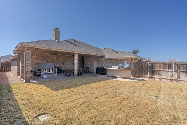 rear view of property featuring a patio, a yard, a fenced backyard, and brick siding