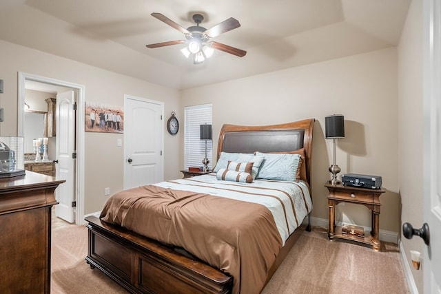 bedroom with ensuite bathroom, ceiling fan, light carpet, and baseboards