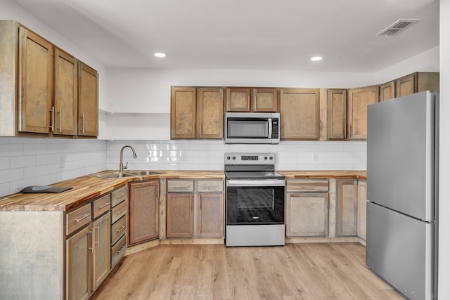 kitchen with wooden counters, visible vents, stainless steel appliances, and a sink