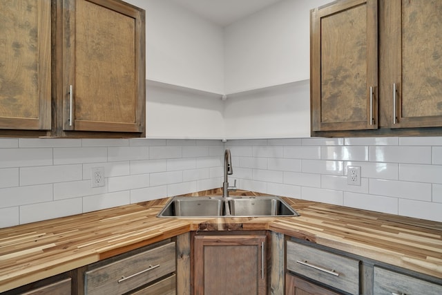 kitchen featuring open shelves, butcher block counters, backsplash, and a sink