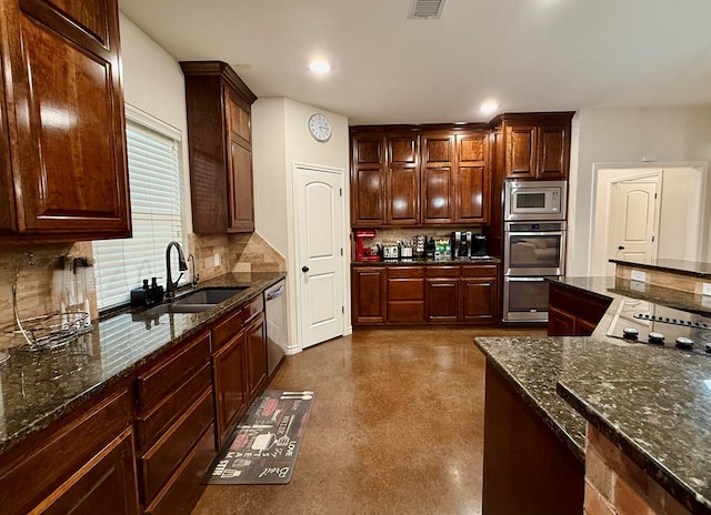 kitchen featuring appliances with stainless steel finishes, sink, dark stone countertops, and backsplash