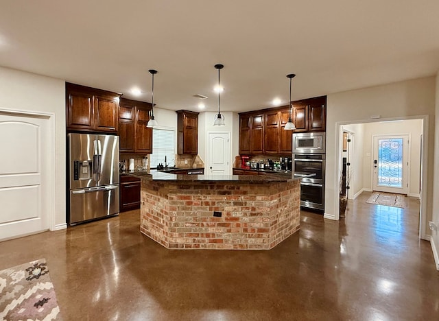 kitchen with pendant lighting, appliances with stainless steel finishes, a center island, and tasteful backsplash