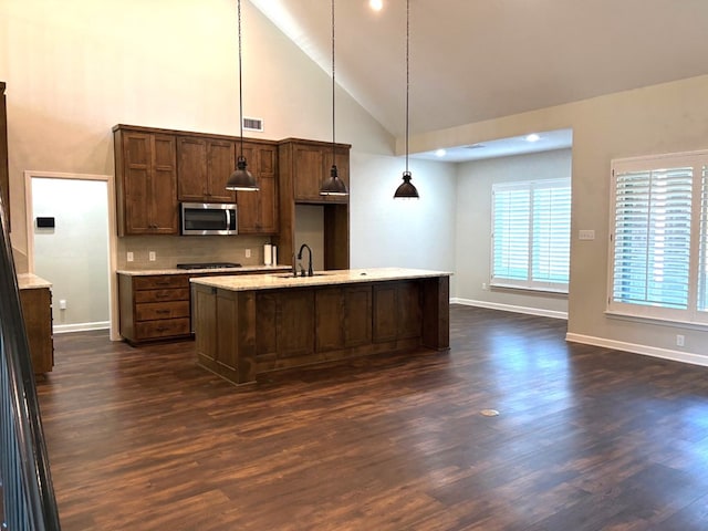 kitchen featuring dark hardwood / wood-style floors, a kitchen island with sink, hanging light fixtures, and sink