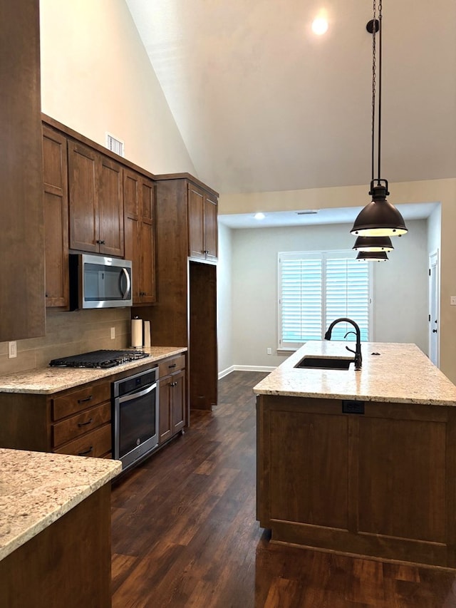 kitchen featuring light stone counters, stainless steel appliances, and decorative light fixtures