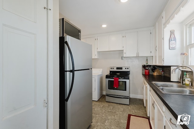 kitchen with dark countertops, washer / clothes dryer, appliances with stainless steel finishes, white cabinets, and a sink